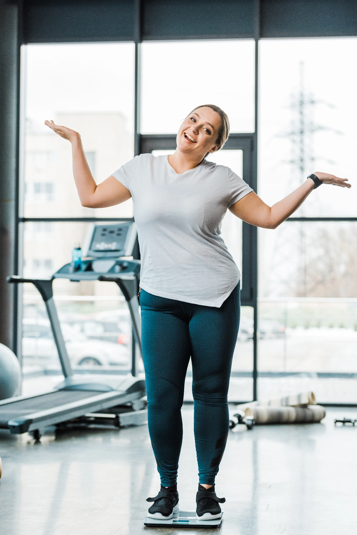 Happy woman standing on a scale in a gym