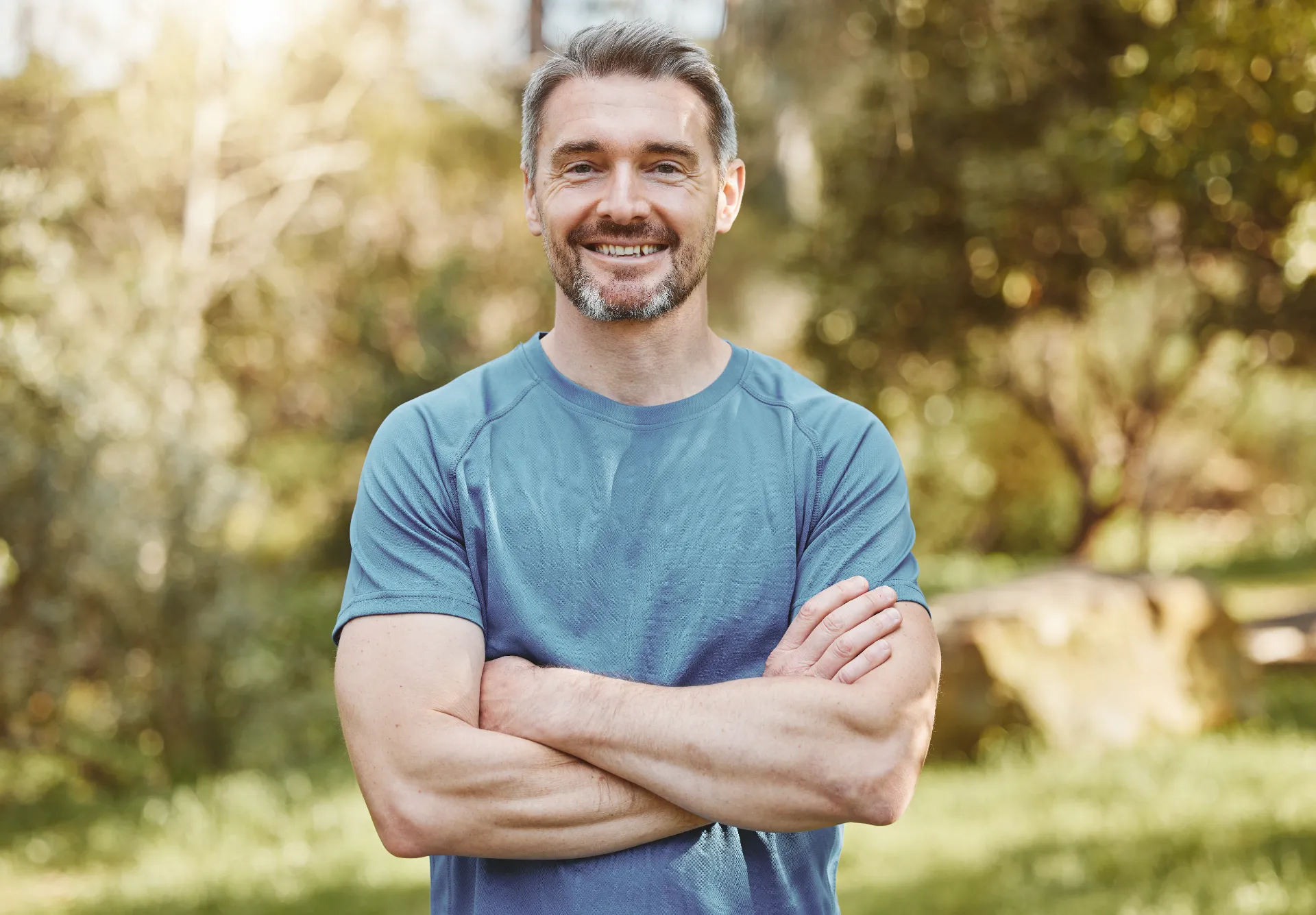 Smiling man with arms crossed outdoors